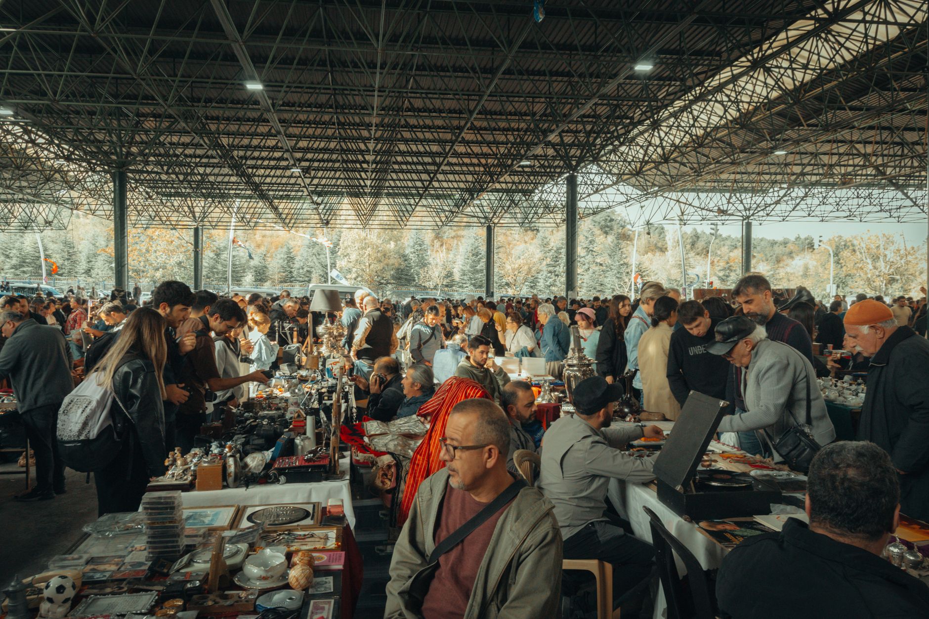 Bustling flea market with diverse crowd under a metal canopy, showcasing various goods. — Coronavirus disease 2019
