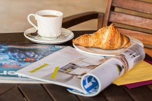 Enjoy a peaceful morning with coffee, croissant, and reading material on a wooden table. — Die allgemeine Benutzerfreundlichk