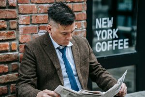 Man in formal attire reading a newspaper outside New York coffee shop. — Les meilleures innovations technologiques chez Lucky