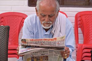 Elderly man engaging in daily reading of a newspaper while seated outdoors. — Nelspin Casino: Quick Mobile Play for Fast Wins