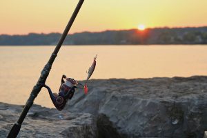 Fishing rod and lure at sunrise on a rocky pier in Webster Lake, NY. — Was macht die Spiele im Azur Slot Casino so besonders?